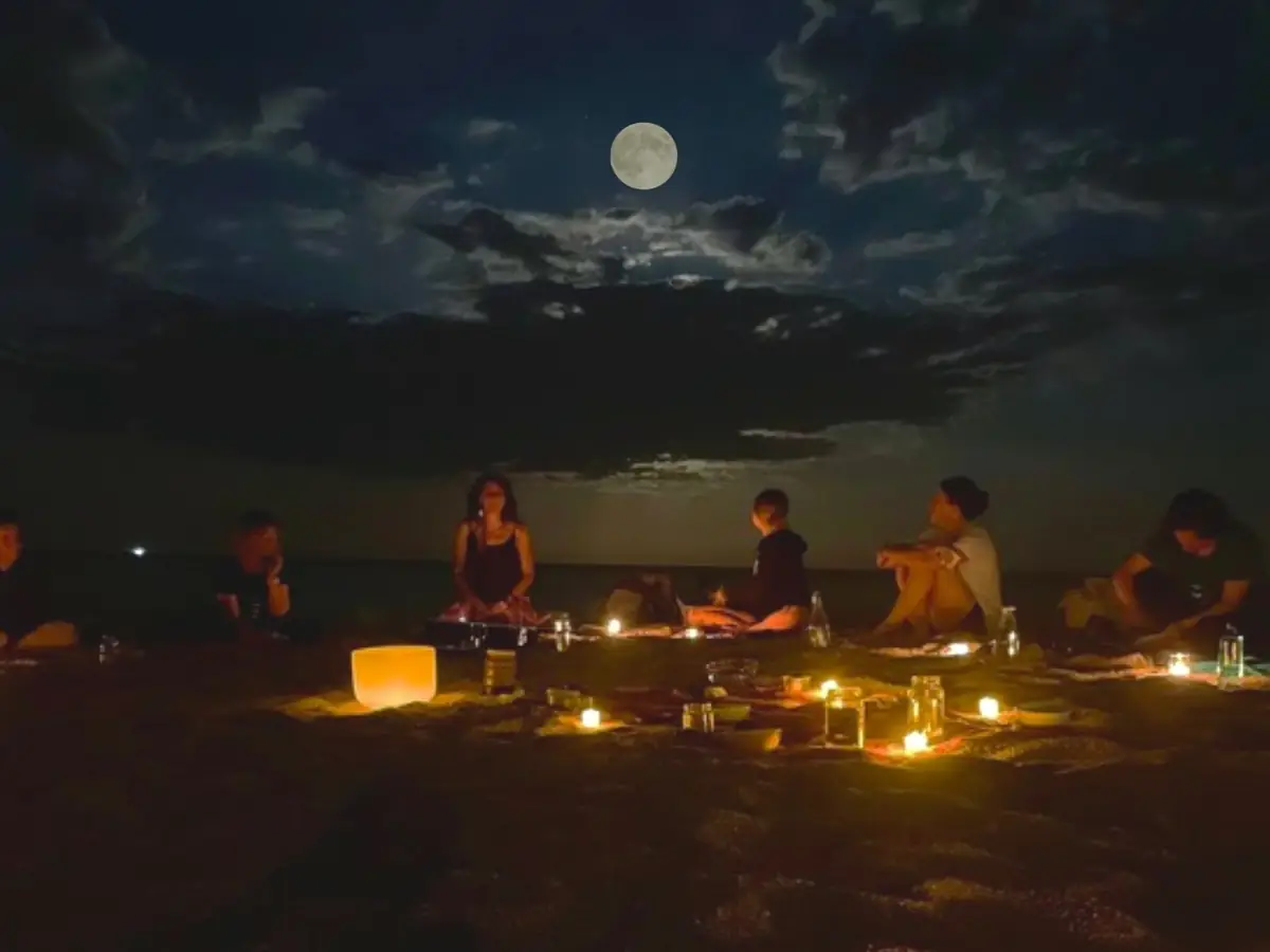 Círculo de mujeres bajo la luna llena en la playa