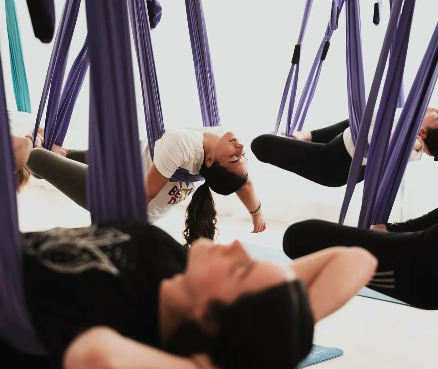 Alumnas descansando en la tela durante una clase de yoga aéreo