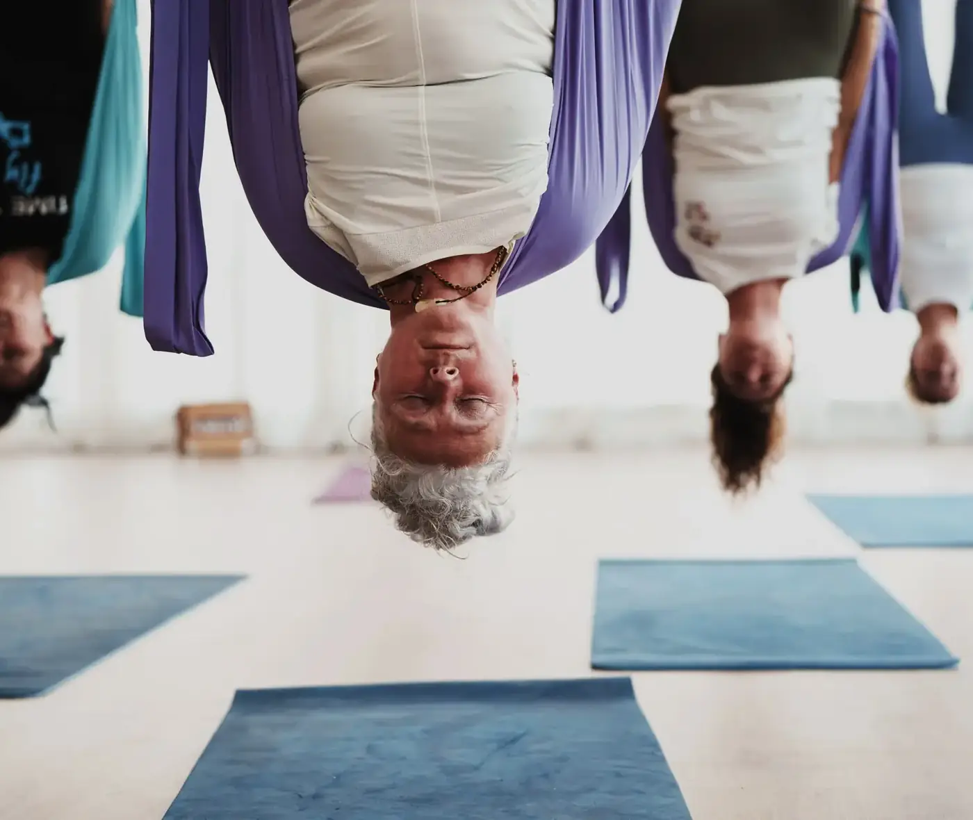 Alumnas invertidas en la tela durante una clase de yoga aéreo