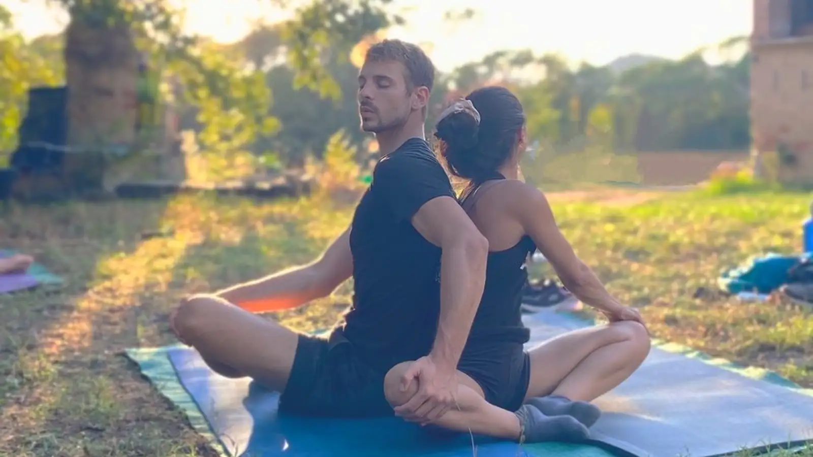 Pareja meditando espalda con espalda al atardecer en Laranahata